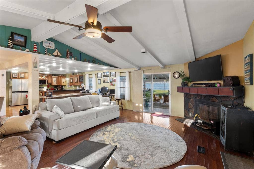 308 Causeway Cove, Seven Points, TX 75143 Vaulted ceiling with exposed beams, wood-finish flooring, stone-faced fireplace, and sliding glass doors