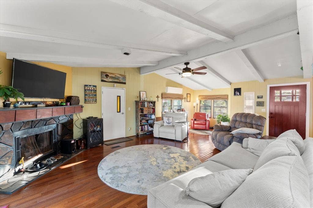 308 Causeway Cove, Seven Points, TX 75143 Vaulted ceiling with exposed beams, wood-finish flooring, stone-clad fireplace with mantel, ceiling fan, and red wood-paneled entry door