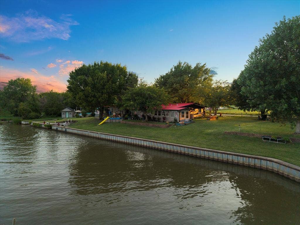 308 Causeway Cove, Seven Points, TX 75143 Waterfront property at full pool featuring a red roof and mature trees