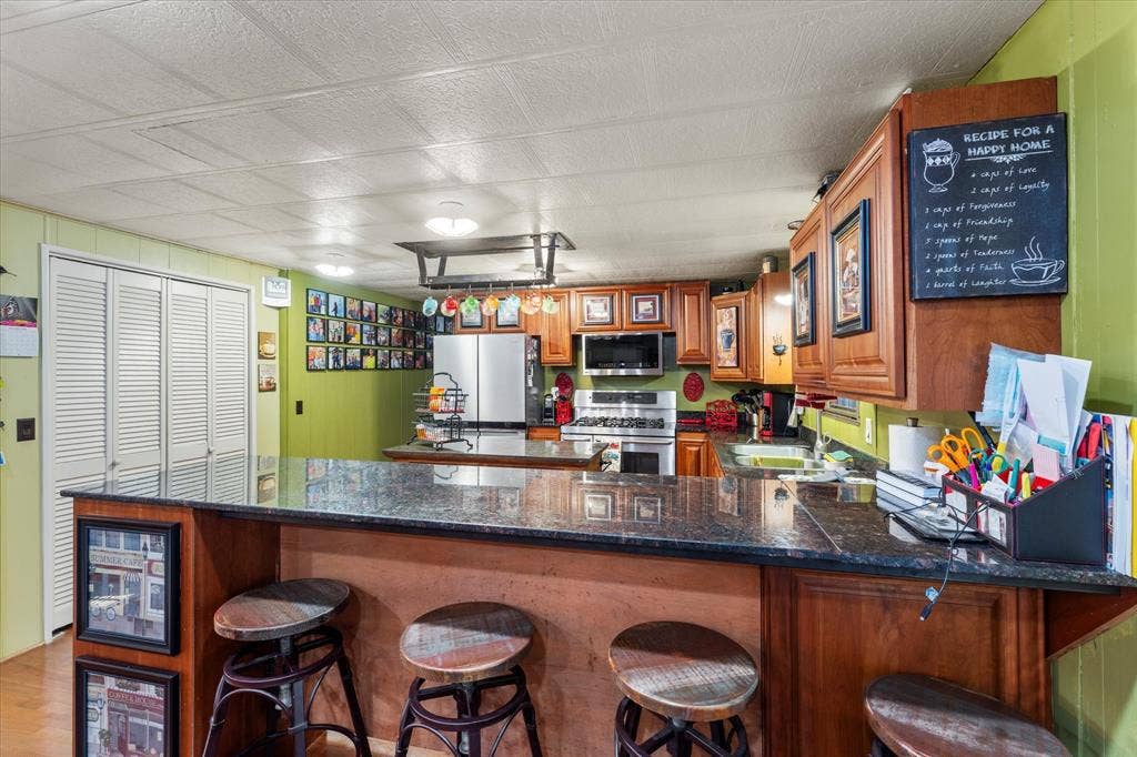 308 Causeway Cove, Seven Points, TX 75143 Kitchen featuring a breakfast bar with dark countertops, wood-finish cabinetry, built-in stainless steel appliances, and a wall-mounted pot rack
