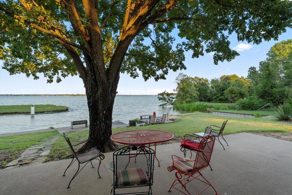 308 Causeway Cove, Seven Points, TX 75143 Expansive waterfront property featuring a concrete patio, mature trees, and a grassy area with natural landscaping