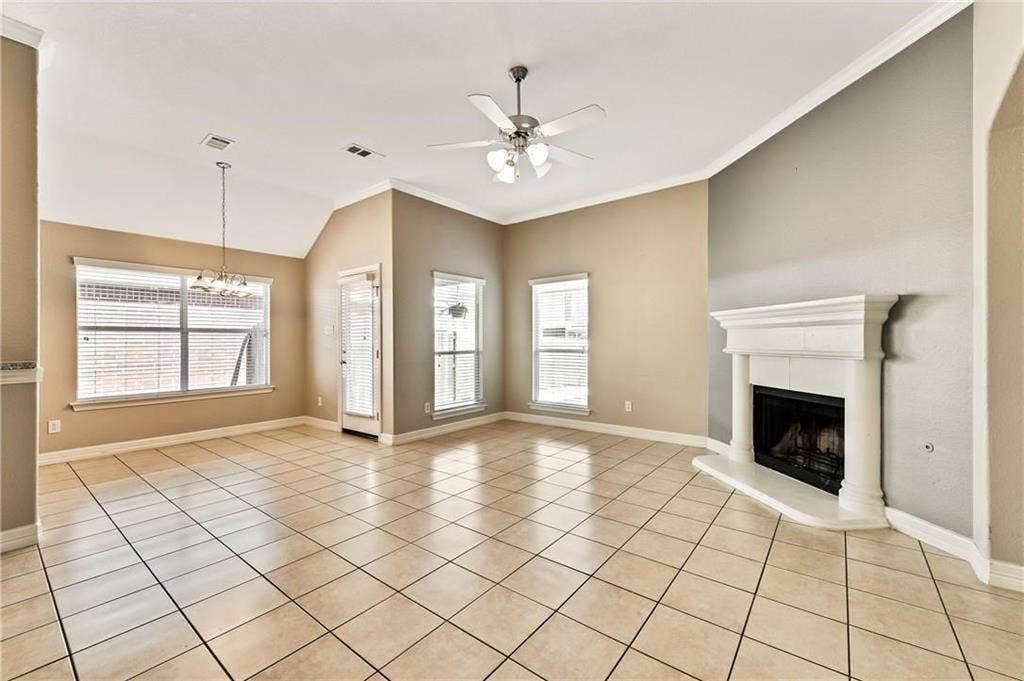 4637 Dwarf Nettle Drive, Fort Worth, TX 76244 Spacious living area featuring tile flooring, vaulted ceilings, a fireplace with a white mantel, and multiple windows with blinds