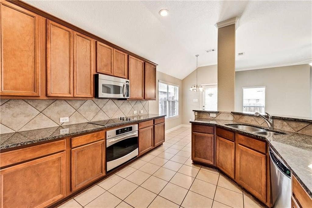 4637 Dwarf Nettle Drive, Fort Worth, TX 76244 Kitchen featuring wood cabinetry, stainless steel appliances, granite countertops, and a tiled backsplash