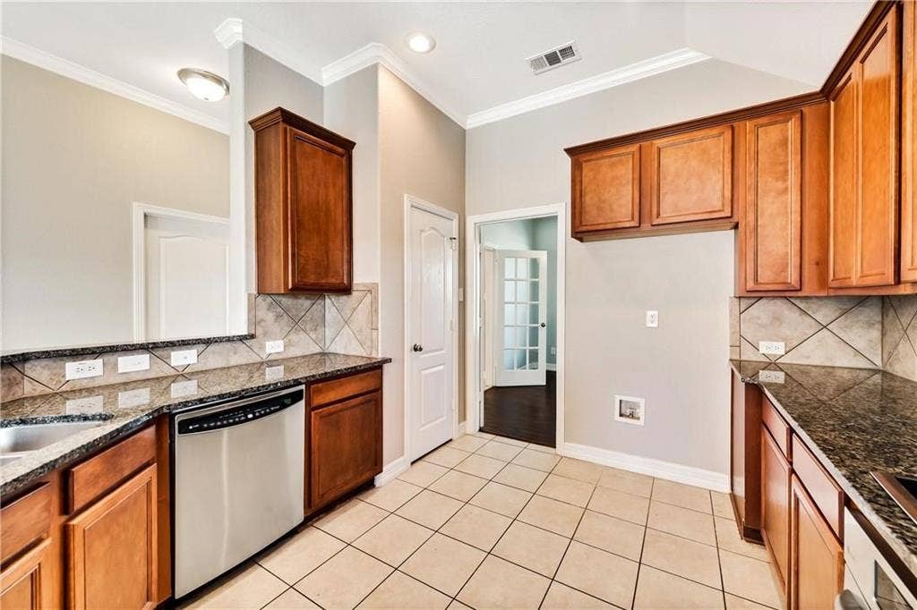 4637 Dwarf Nettle Drive, Fort Worth, TX 76244 Kitchen featuring tile flooring, granite countertops, wood cabinetry, a stainless steel dishwasher, and a tile backsplash