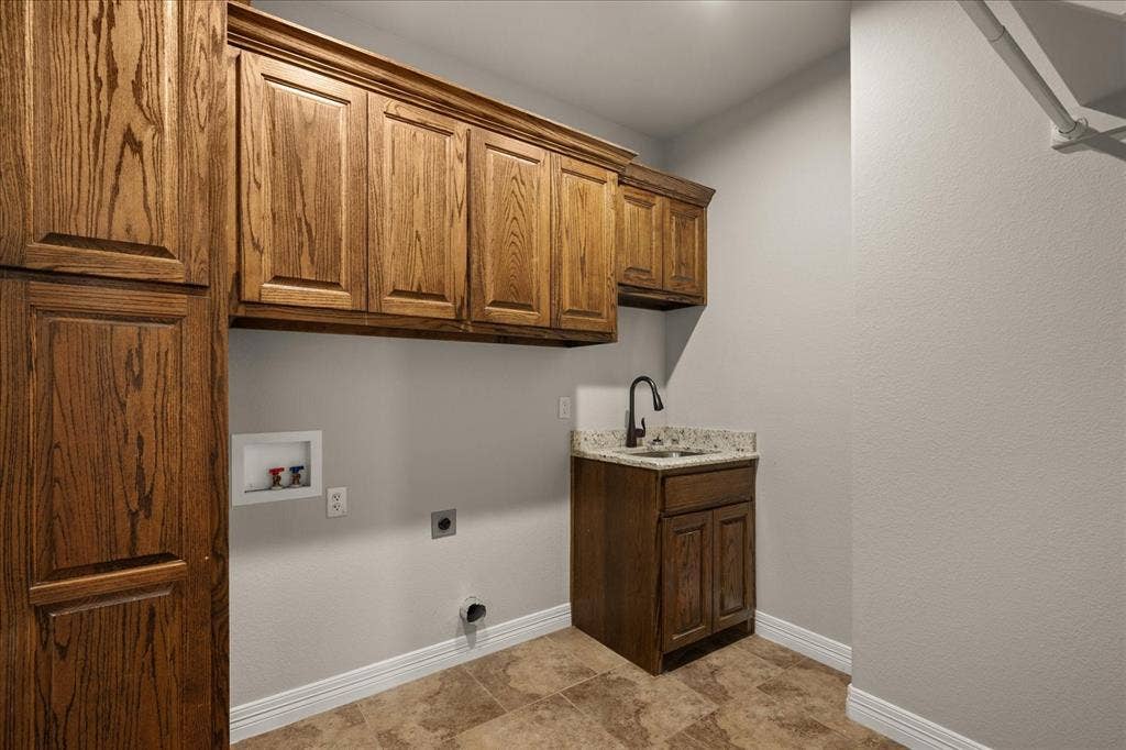 3674 County Road 2142, Caddo Mills, TX 75135 Wood-finish cabinetry, built-in sink with dark-toned faucet, light-toned walls, tiled flooring, and ample storage