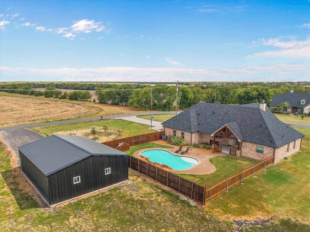 3674 County Road 2142, Caddo Mills, TX 75135 Brick exterior residence featuring a gabled roof, an inground swimming pool, and an outdoor patio space