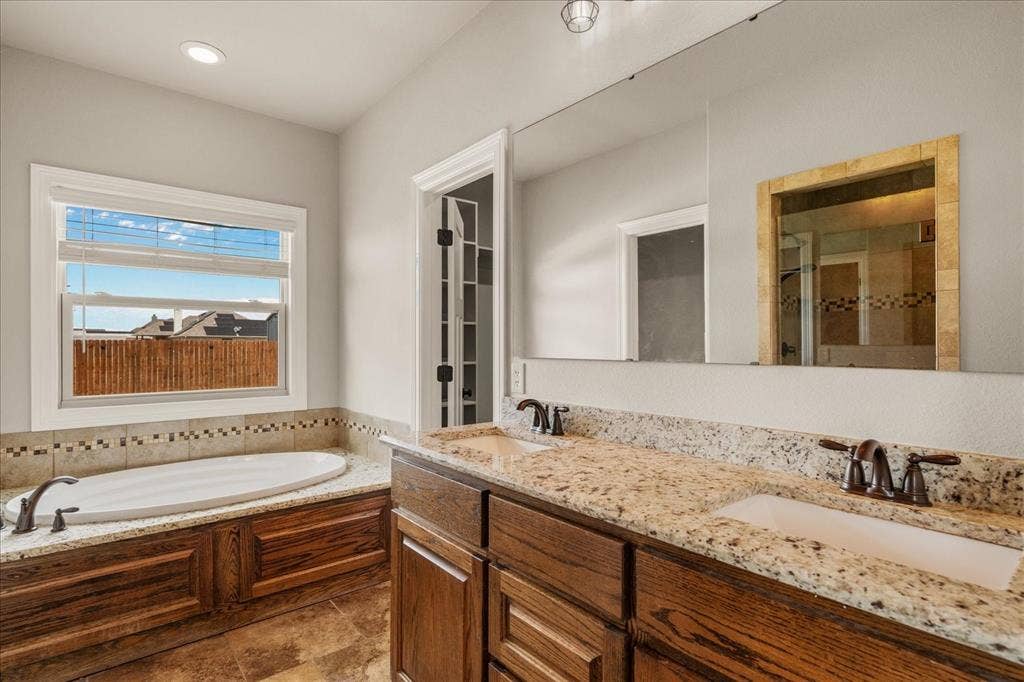 3674 County Road 2142, Caddo Mills, TX 75135 Dual vanity with granite-style countertops, wood-finish cabinetry, and undermount sinks