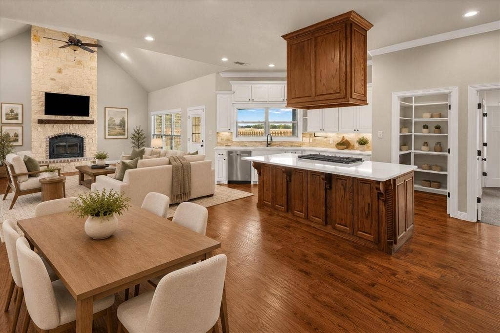 3674 County Road 2142, Caddo Mills, TX 75135 Vaulted ceilings, wood-finish flooring, stone-clad fireplace with mantel, kitchen island with built-in gas cooktop, and built-in shelving