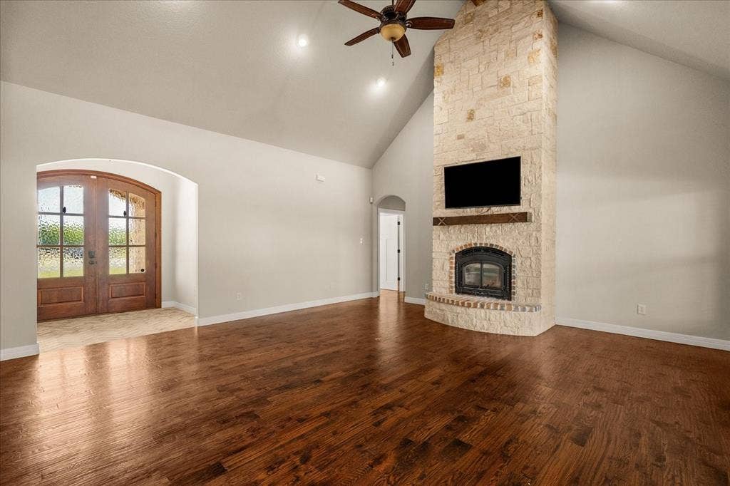 3674 County Road 2142, Caddo Mills, TX 75135 Vaulted ceiling, stone-clad fireplace, wood-finish flooring, arched doorway, and double entry doors