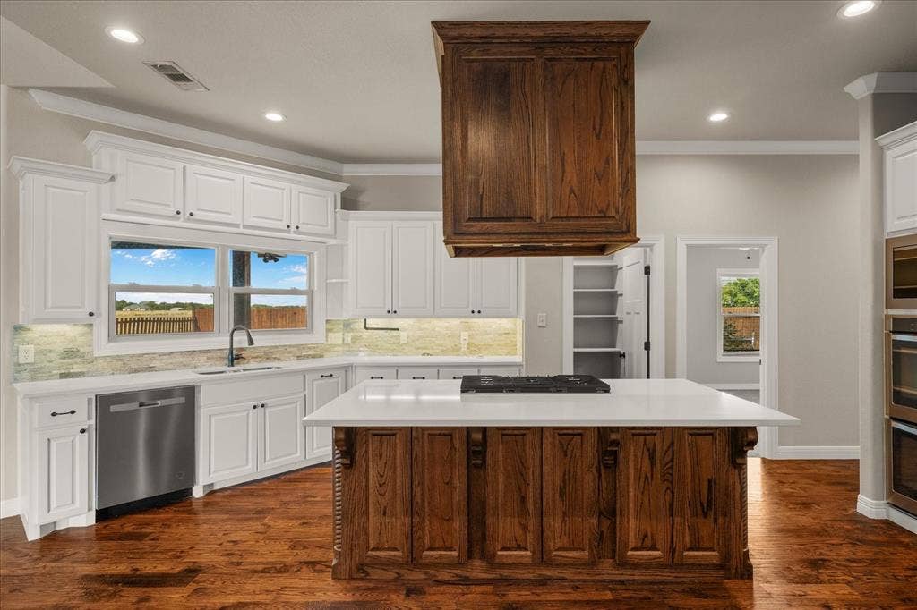 3674 County Road 2142, Caddo Mills, TX 75135 Gourmet kitchen with wood-finish flooring, white cabinetry, a large center island with a cooktop, and stainless steel appliances including a built-in oven and dishwasher