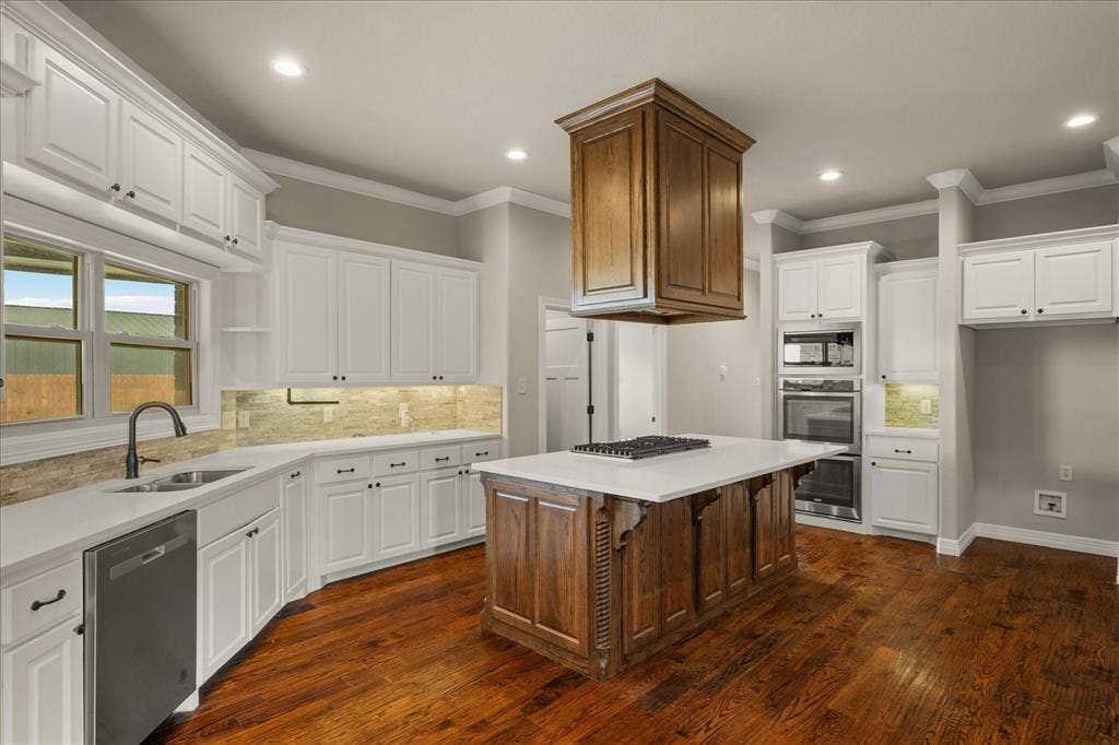 3674 County Road 2142, Caddo Mills, TX 75135 Wood-finish flooring, white cabinetry, a center island with a cooktop, a built-in oven, and a built-in microwave