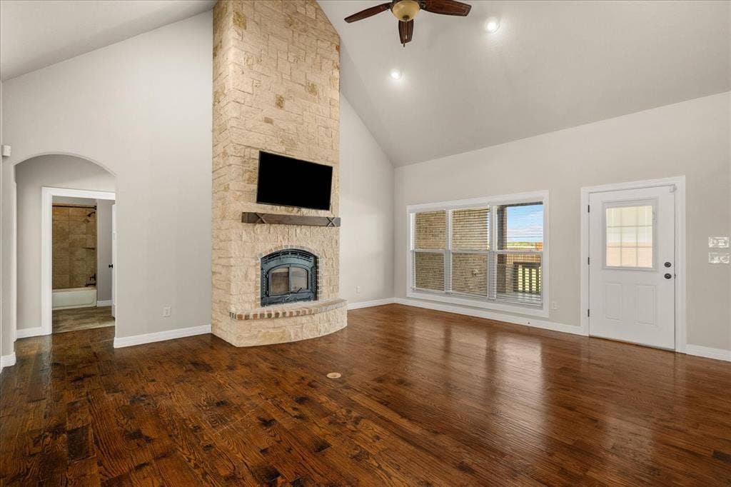 3674 County Road 2142, Caddo Mills, TX 75135 Vaulted ceiling, stone-clad fireplace with hearth, wood-finish flooring, ceiling fan, and exterior access