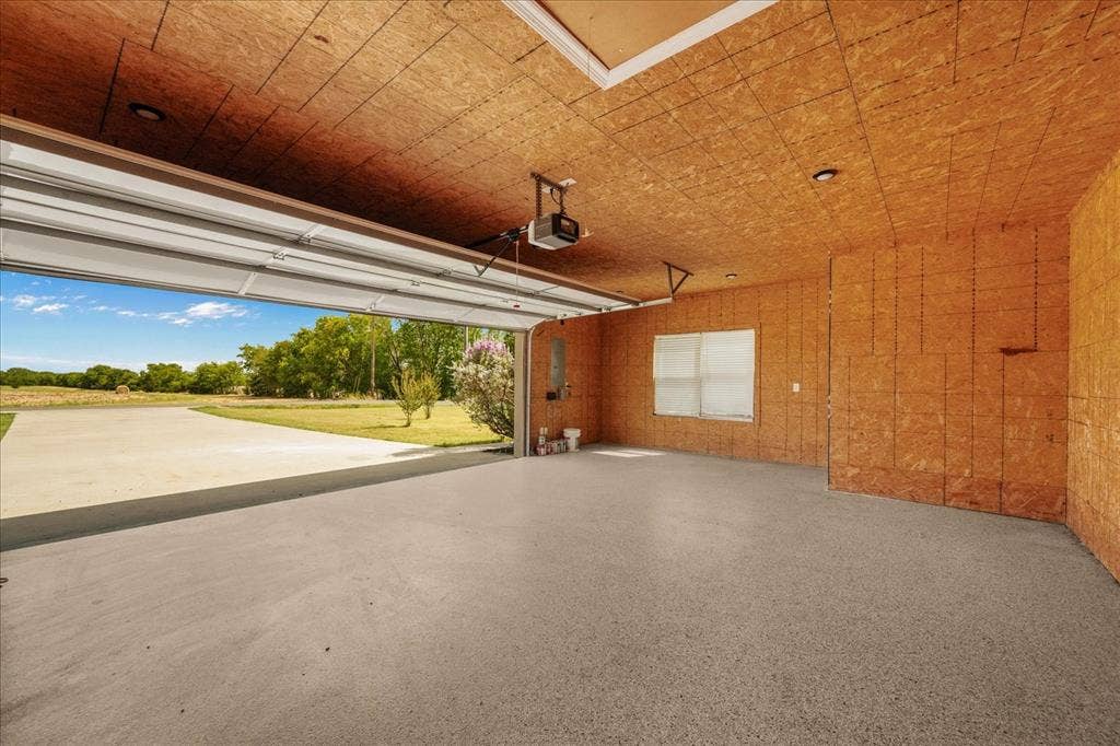 3674 County Road 2142, Caddo Mills, TX 75135 Spacious garage featuring a durable concrete floor, overhead door, and a single window
