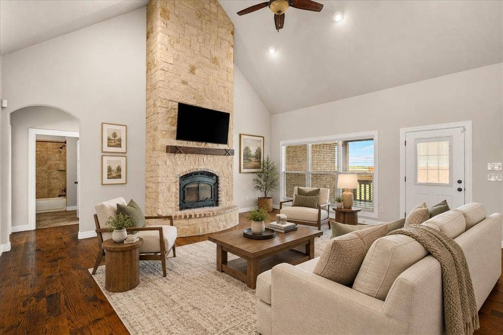 3674 County Road 2142, Caddo Mills, TX 75135 Vaulted ceiling, stone fireplace with hearth, wood-finish flooring, ceiling fan, and transom windows