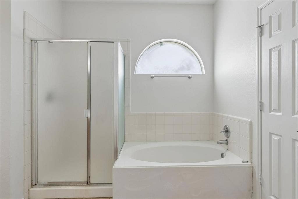6508 Courtyards Drive, McKinney, TX 75072 Built-in soaking tub with chrome fixtures, tiled surround, and frosted arch window