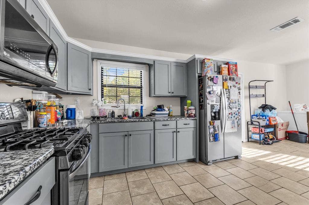 3605 Rolando Avenue, Waco, TX 76711 Kitchen featuring light gray cabinetry, dark speckled countertops, stainless steel appliances, and a window above the sink