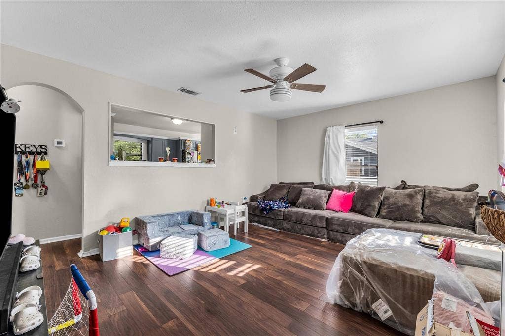 3605 Rolando Avenue, Waco, TX 76711 Wood-finish flooring throughout, ceiling fan with light fixture, arched doorway, and built-in wall pass-through