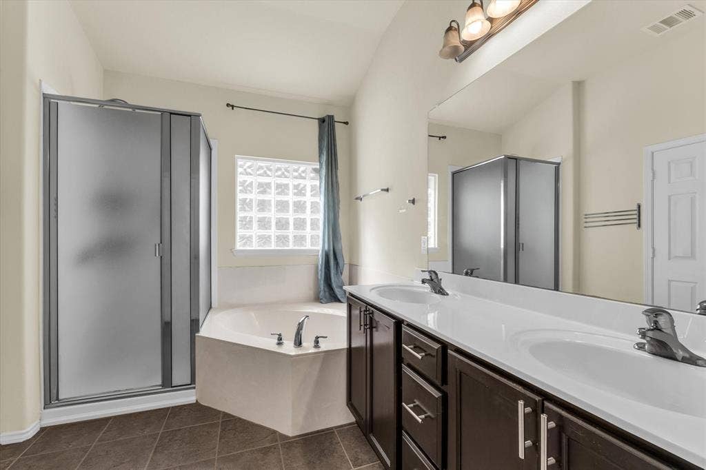6621 Burling Street, Waco, TX 76712 Dual vanity with integrated sinks, corner soaking tub, glass block window, and separate frosted glass shower enclosure