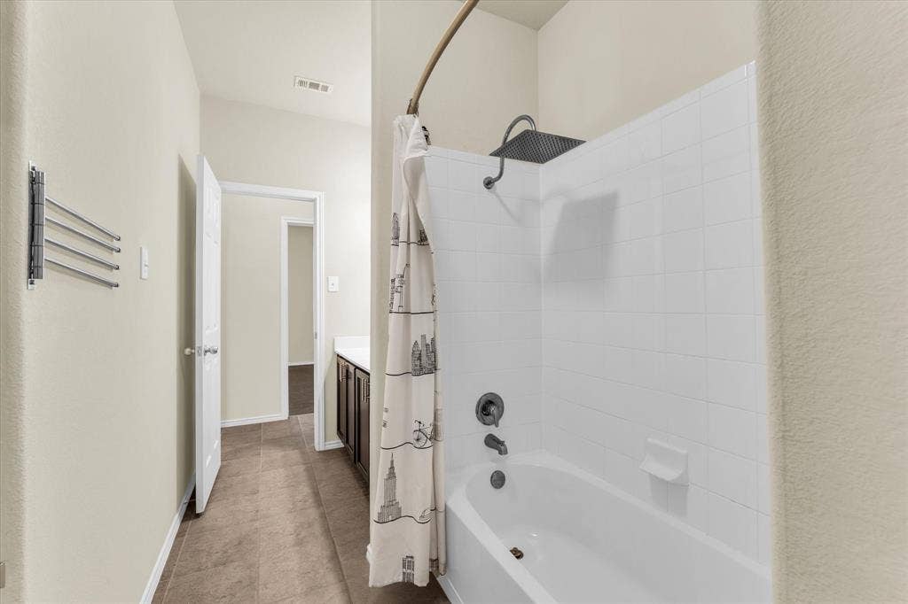 6621 Burling Street, Waco, TX 76712 Bathtub with white tile surround, rainfall showerhead, and dark bronze fixtures