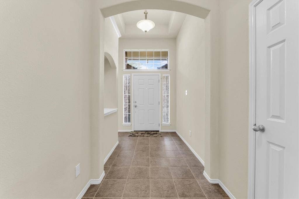 6621 Burling Street, Waco, TX 76712 Entryway featuring tiled flooring, an arched doorway, and a white paneled door with sidelights and a transom window