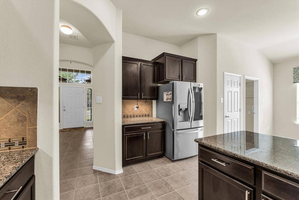 6621 Burling Street, Waco, TX 76712 Kitchen featuring dark wood-finish cabinetry, granite-style countertops, and a tiled backsplash