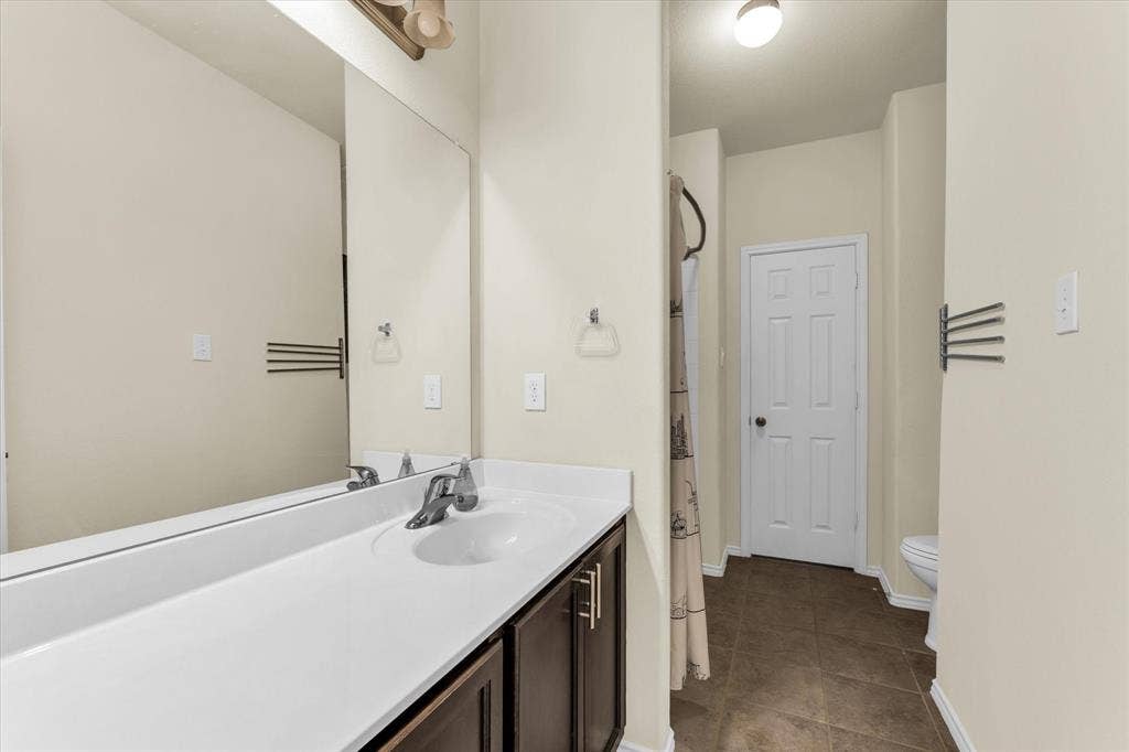 6621 Burling Street, Waco, TX 76712 Vanity with integrated sink, chrome faucet, and brown wood-finish cabinetry