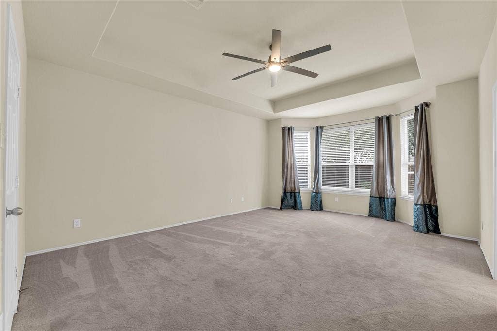 6621 Burling Street, Waco, TX 76712 Tray ceiling with a ceiling fan, bay windows with blinds, and neutral carpet flooring