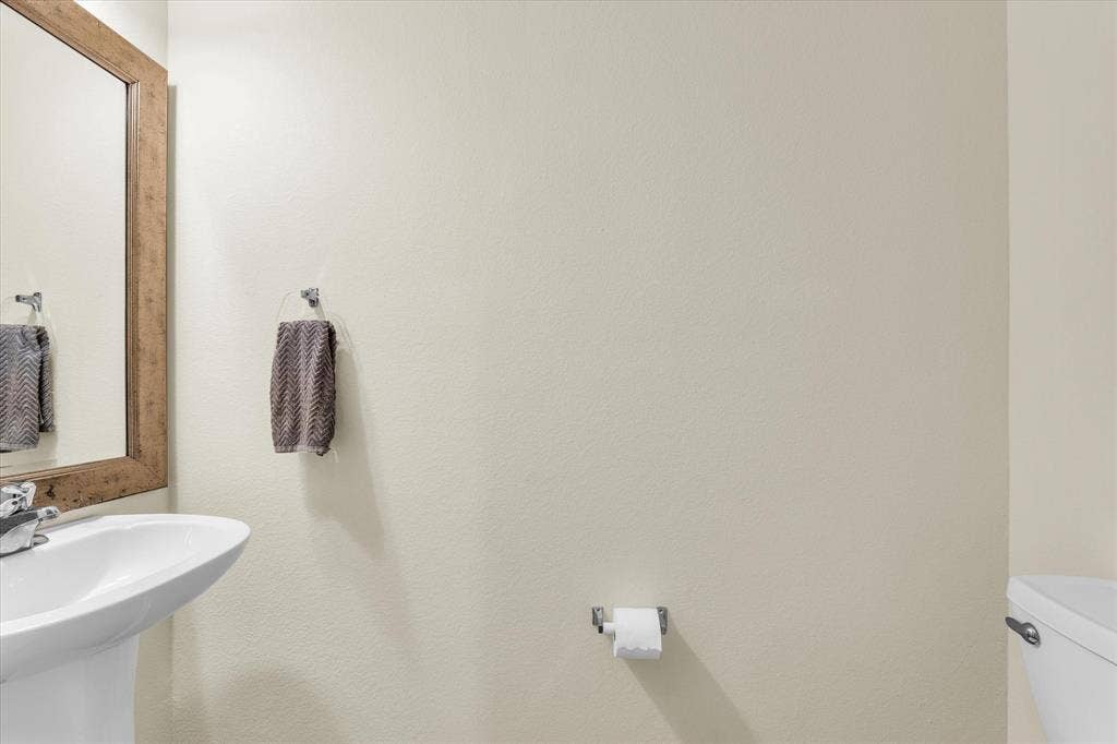 6621 Burling Street, Waco, TX 76712 Pedestal sink, chrome faucet, wood-framed mirror, and chrome towel ring