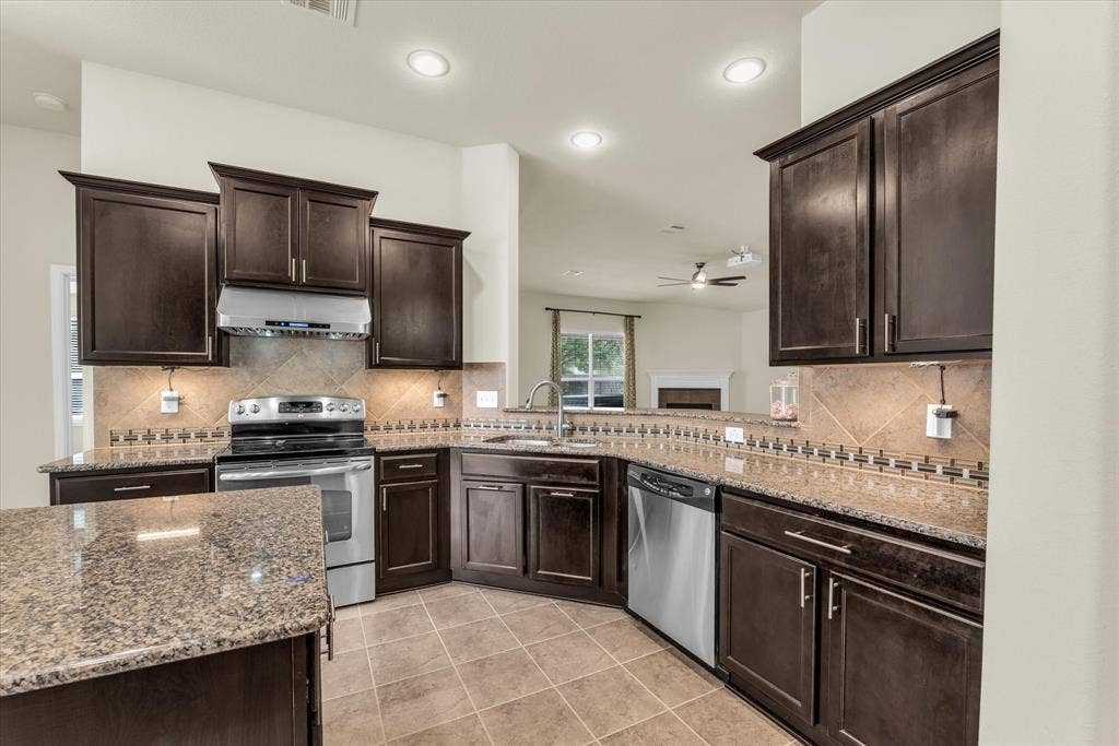 6621 Burling Street, Waco, TX 76712 Kitchen featuring dark wood cabinetry, granite countertops, stainless steel appliances, tile backsplash, and recessed lighting