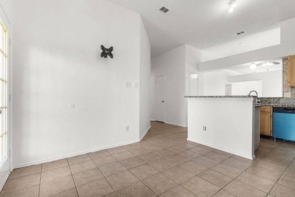 Ceramic tile flooring, vaulted ceilings, and kitchen peninsula featuring a stone-look countertop