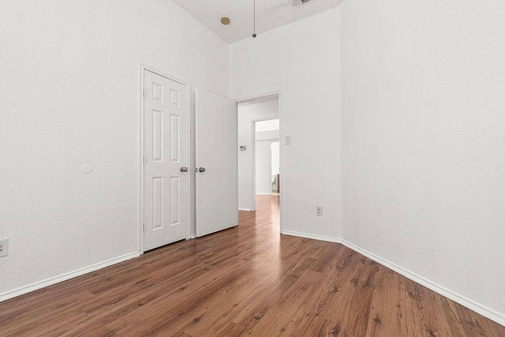 Interior space featuring wood-finish flooring, high ceilings, and white paneled doors