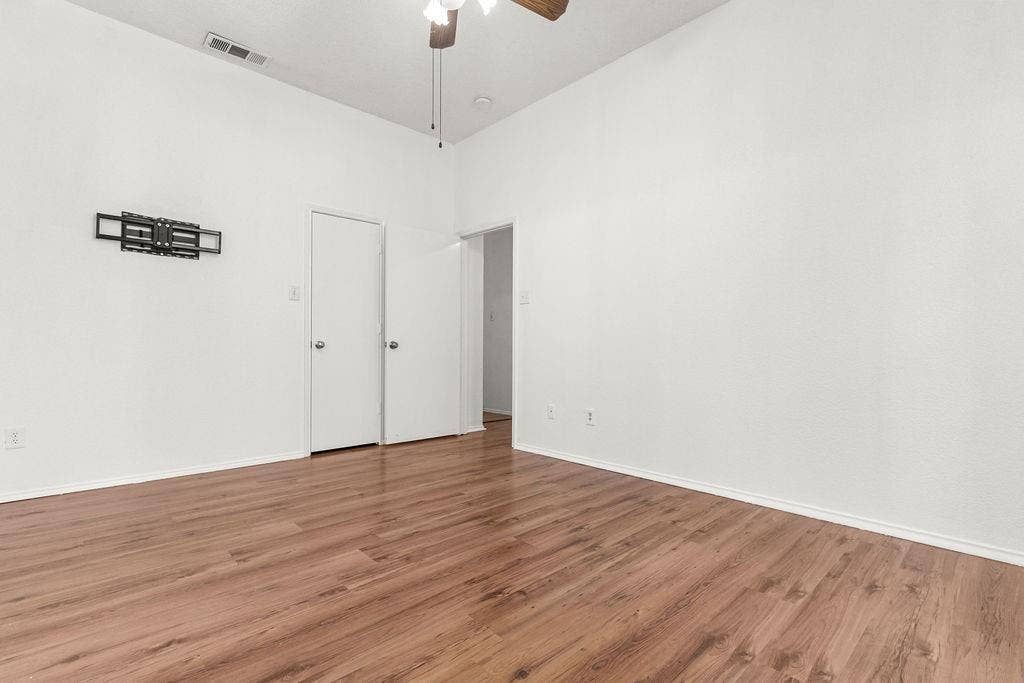High-ceiling interior featuring wood-finish flooring, a central ceiling fan, and neutral wall tones