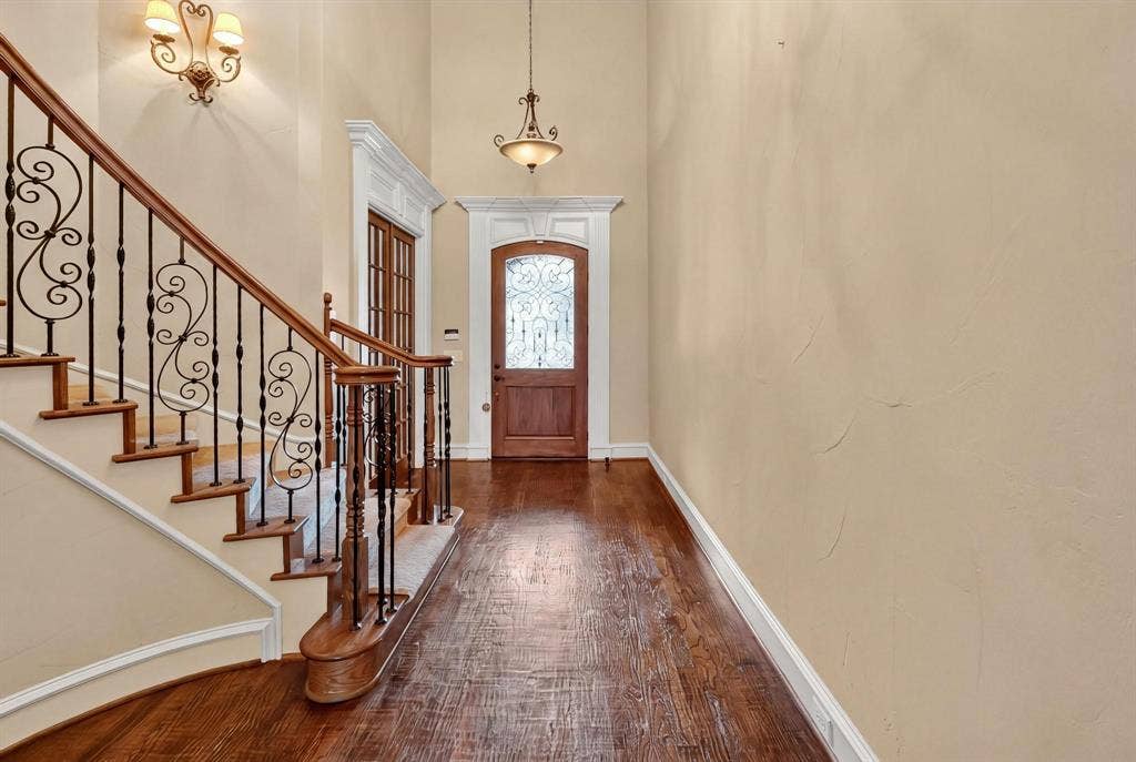112 Winsley Circle, McKinney, TX 75071 Hardwood flooring, curved staircase with wrought iron balusters, elegant entry door with decorative glass, and crown molding