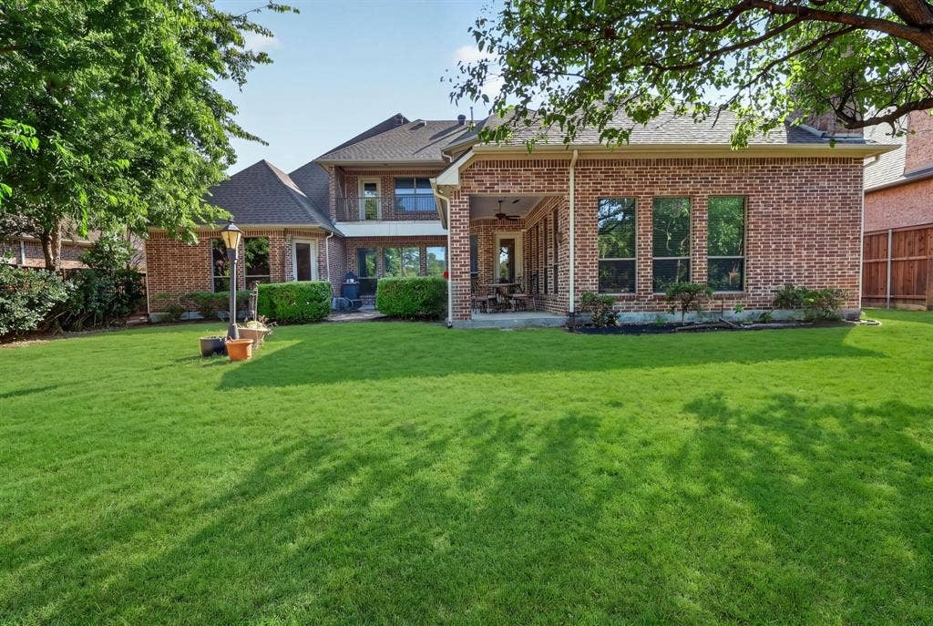 112 Winsley Circle, McKinney, TX 75071 Expansive backyard with water view featuring, brick exterior, covered patio, and mature trees. Virtually Staged