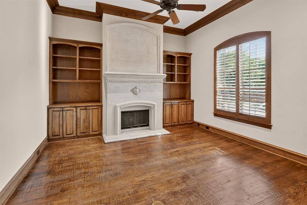 112 Winsley Circle, McKinney, TX 75071 Front formal living or office with stone fireplace with hearth, hand scraped wood flooring, and built-in wooden cabinetry.