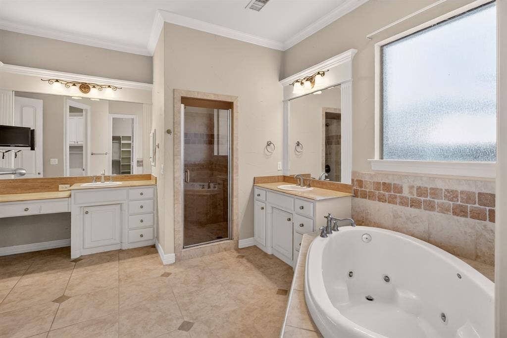 112 Winsley Circle, McKinney, TX 75071 Primary Ensuite. Dual vanity with light-colored cabinetry, built-in soaking tub, tiled shower enclosure with glass door, and patterned tile flooring