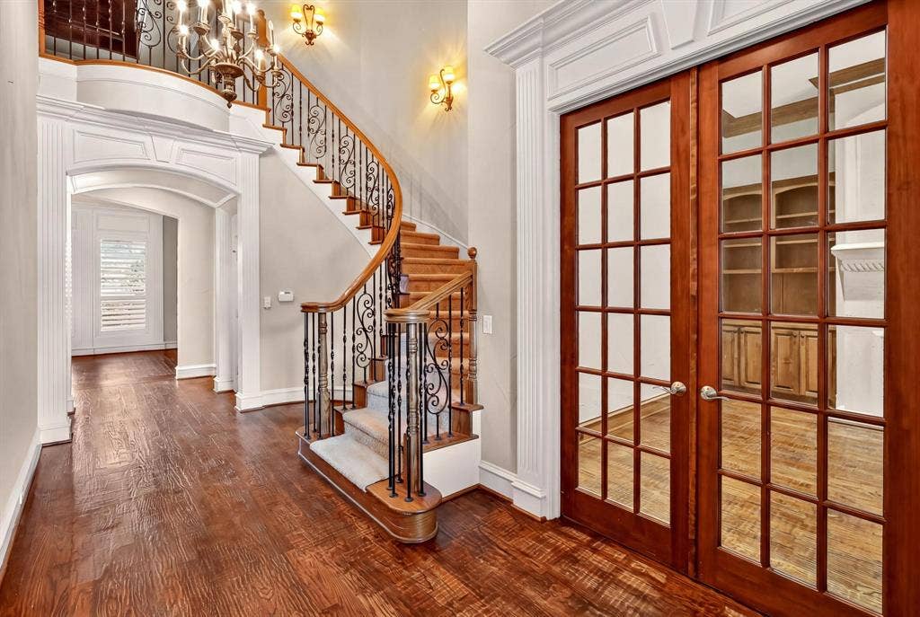 112 Winsley Circle, McKinney, TX 75071 Gracious entry featuring wood-finish flooring, a grand curved staircase with wrought iron balusters, and elegant archways
