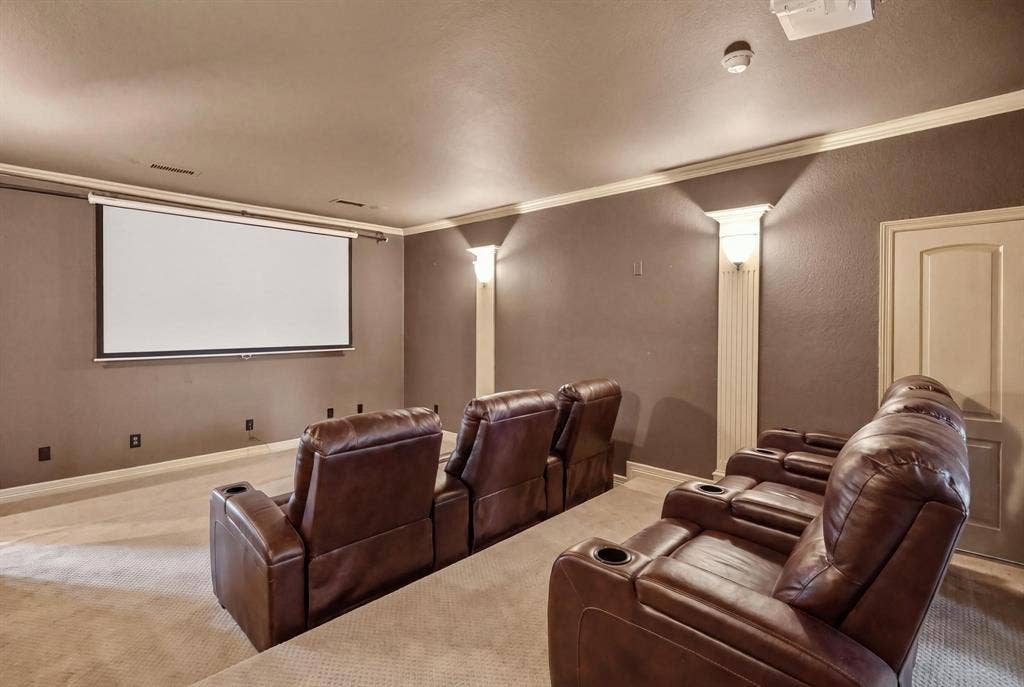 112 Winsley Circle, McKinney, TX 75071 Dedicated two tier media room with a projector screen, wall sconces, ceiling crown molding, and light-colored carpeting. Virtually Staged