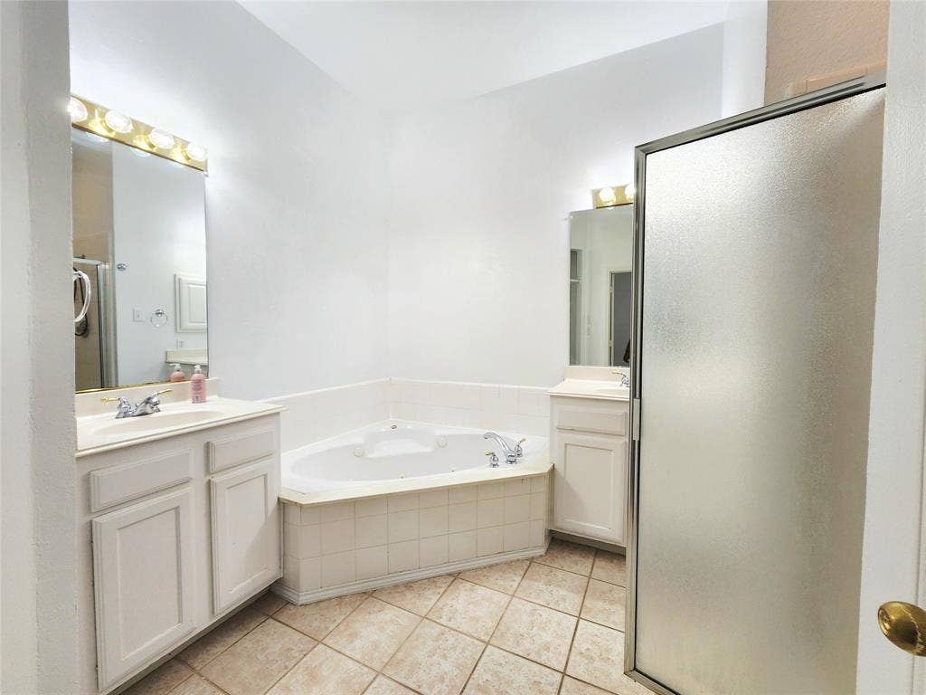 10307 Asheboro Street, Frisco, TX 75035 Dual vanity sinks with mounted mirrors, corner soaking tub, and enclosed shower with frosted glass