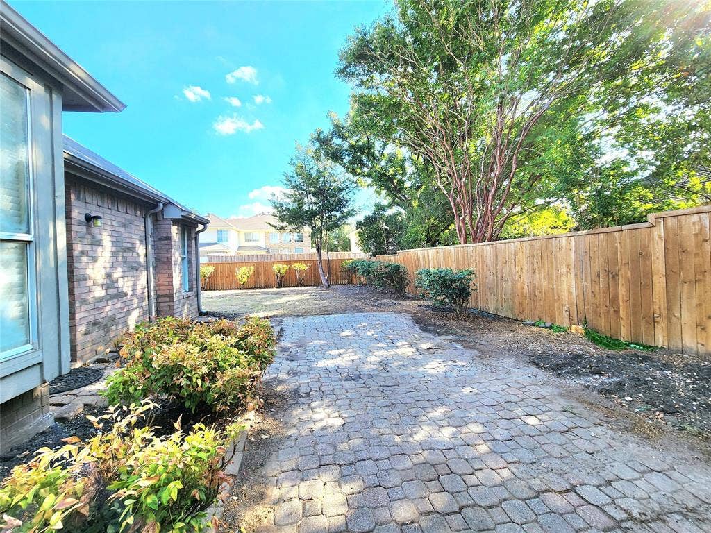 10307 Asheboro Street, Frisco, TX 75035 Brick exterior construction, wood privacy fencing, paver stone walkway, mature trees, and established shrubbery