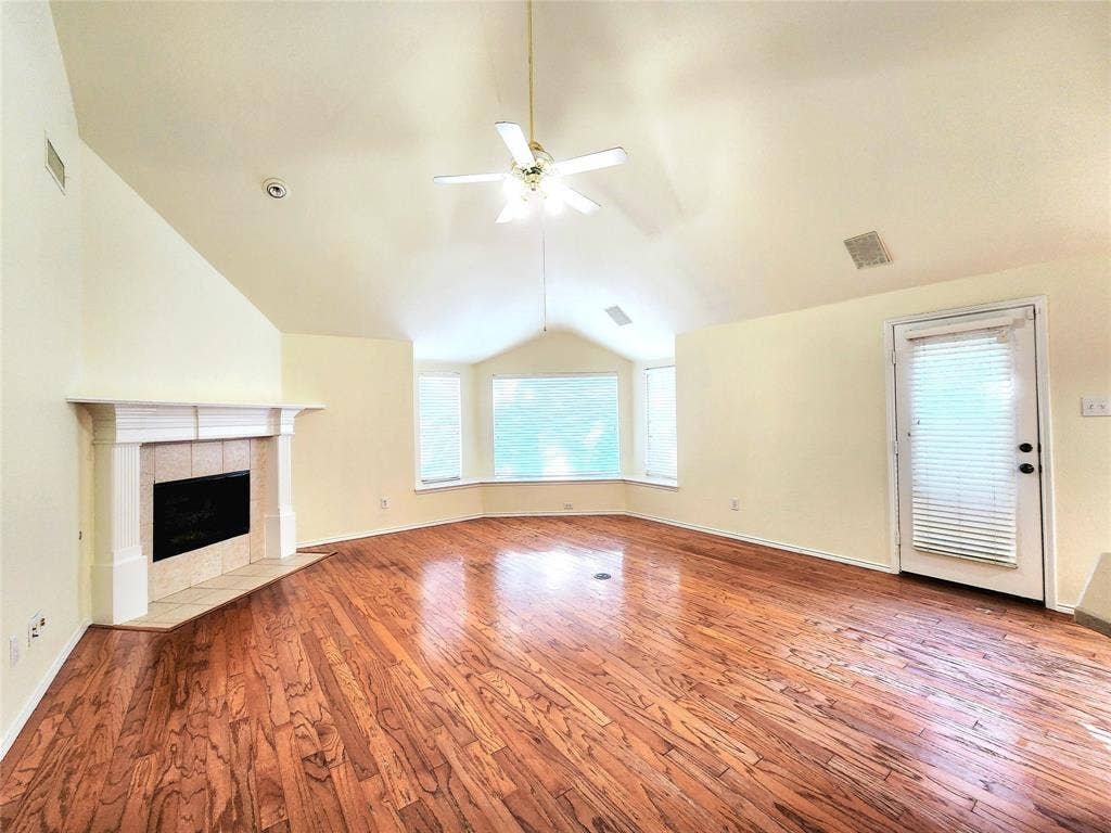 10307 Asheboro Street, Frisco, TX 75035 Vaulted ceiling with a ceiling fan, bay window, wood-finish flooring, and a fireplace with a stone mantel