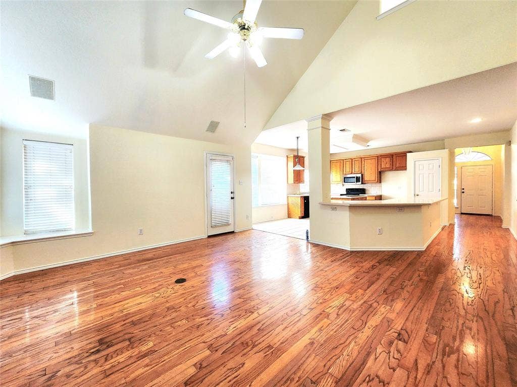 10307 Asheboro Street, Frisco, TX 75035 Vaulted ceiling with a ceiling fan, wood-finish flooring, and a kitchen featuring a breakfast bar