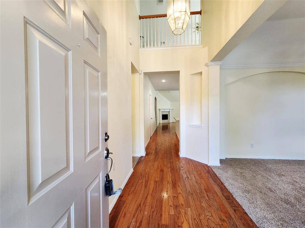 10307 Asheboro Street, Frisco, TX 75035 Two-story foyer with wood-finish flooring, arched doorways, and a decorative chandelier