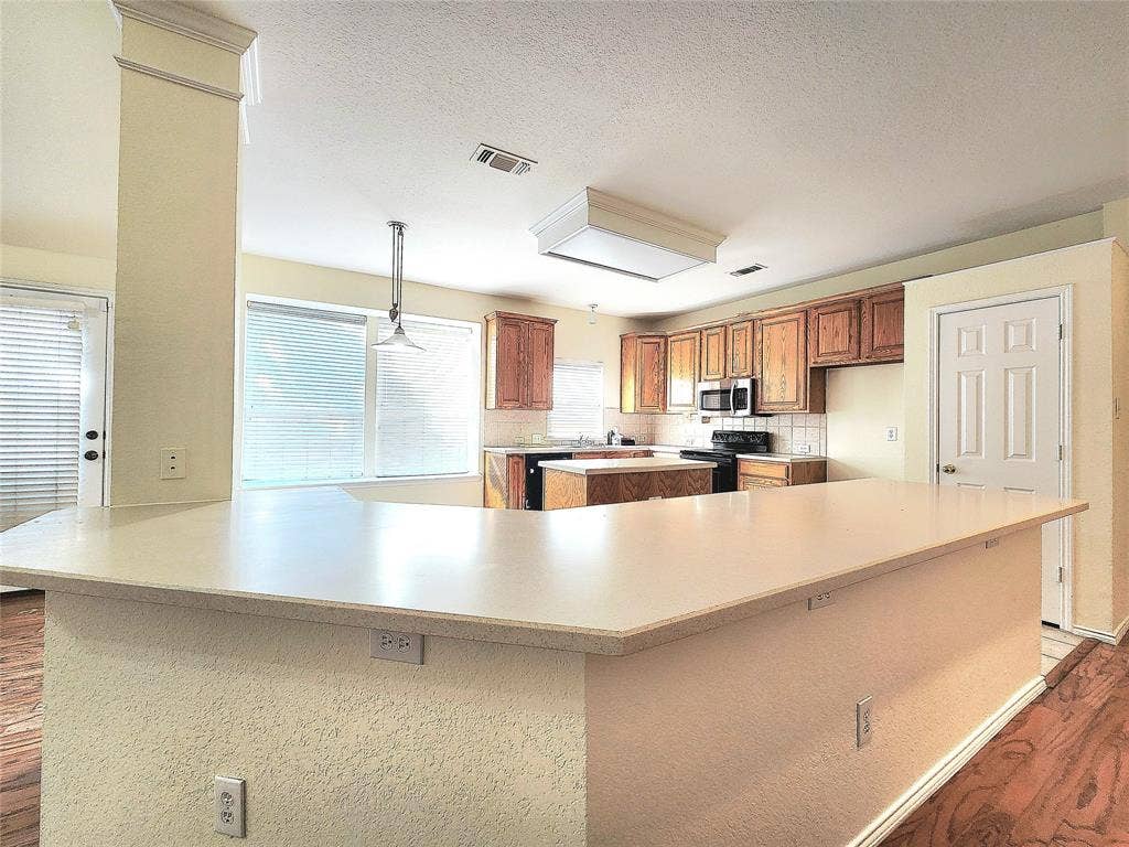 10307 Asheboro Street, Frisco, TX 75035 Kitchen featuring a peninsula with countertop, wood-finish flooring, wood cabinetry, a built-in microwave, and an electric range