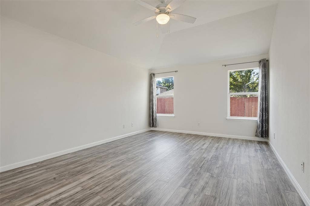 2405 Collier Drive, McKinney, TX 75071 Vaulted ceiling with a ceiling fan, two windows, wood-finish flooring, and light-toned walls