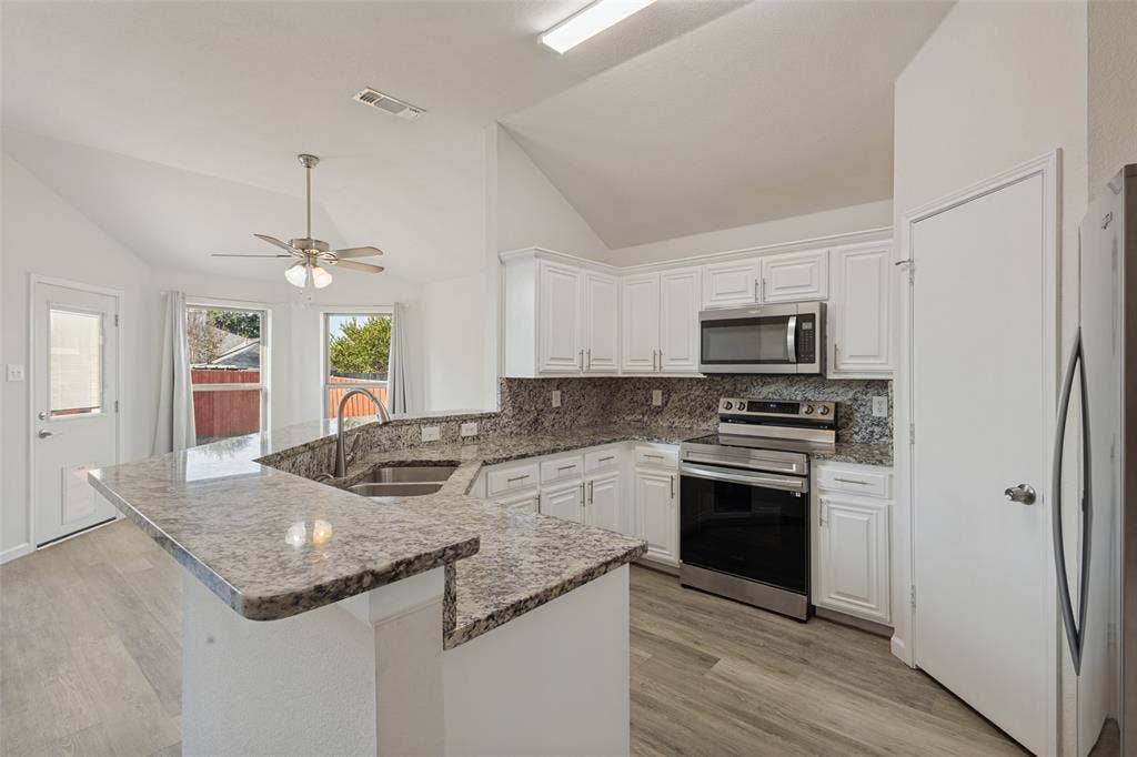2405 Collier Drive, McKinney, TX 75071 Vaulted ceiling, wood-finish flooring, white cabinetry, stainless steel appliances, and granite countertops