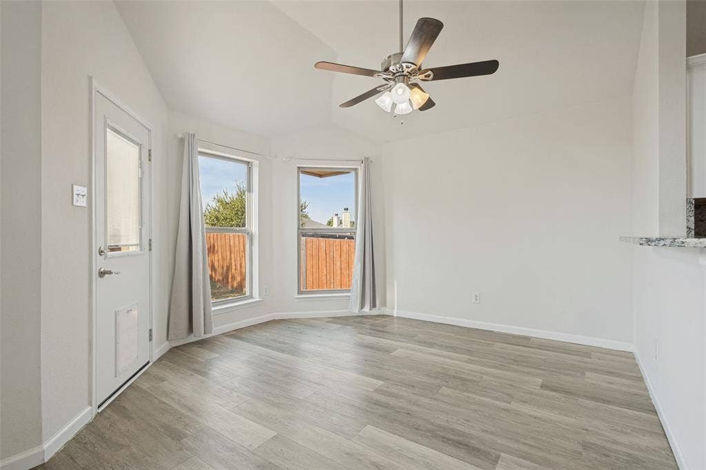 2405 Collier Drive, McKinney, TX 75071 Vaulted ceiling with a ceiling fan, wood-finish flooring, two large windows, and a door with a glass insert