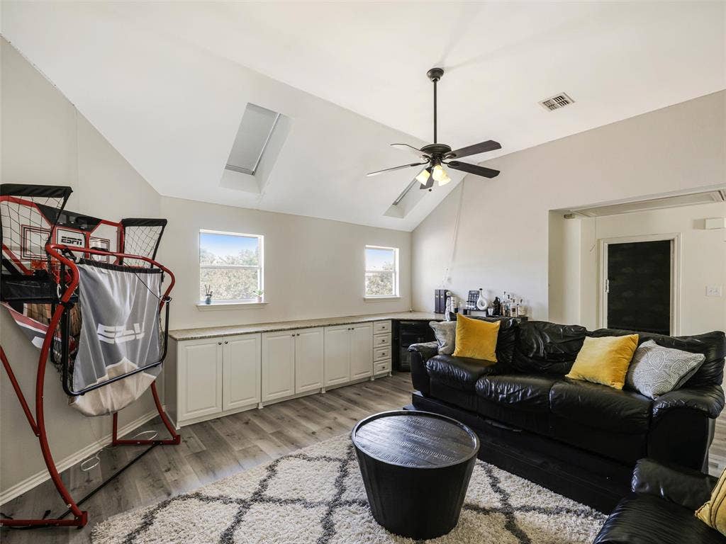 1206 Bel Air Drive, Allen, TX 75013 Vaulted ceiling with skylight, wood-finish flooring, ceiling fan, and built-in white cabinetry with a light-toned countertop