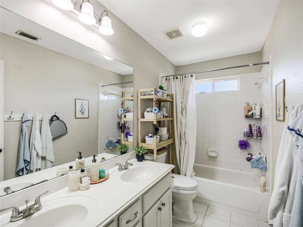 1206 Bel Air Drive, Allen, TX 75013 Dual vanity with integrated sinks, full-width mirror, white tile flooring, and a tub-shower combination with white subway tile surround