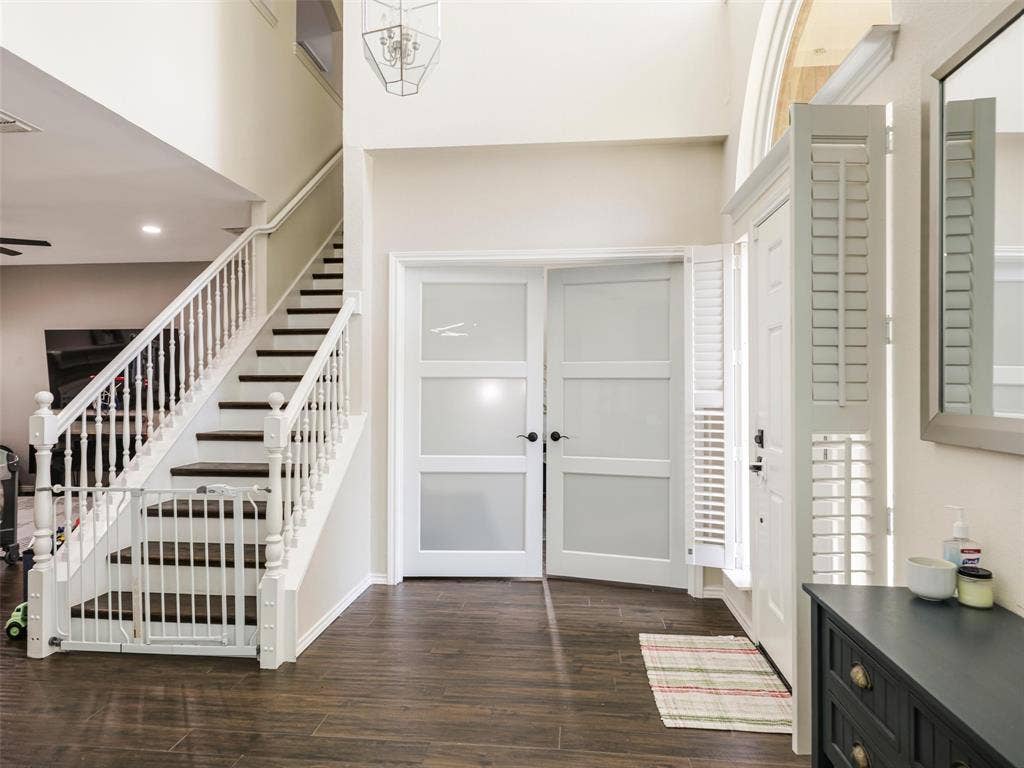 1206 Bel Air Drive, Allen, TX 75013 Two-story entry with wood-finish flooring, a white spindle staircase with dark treads, and a modern chandelier